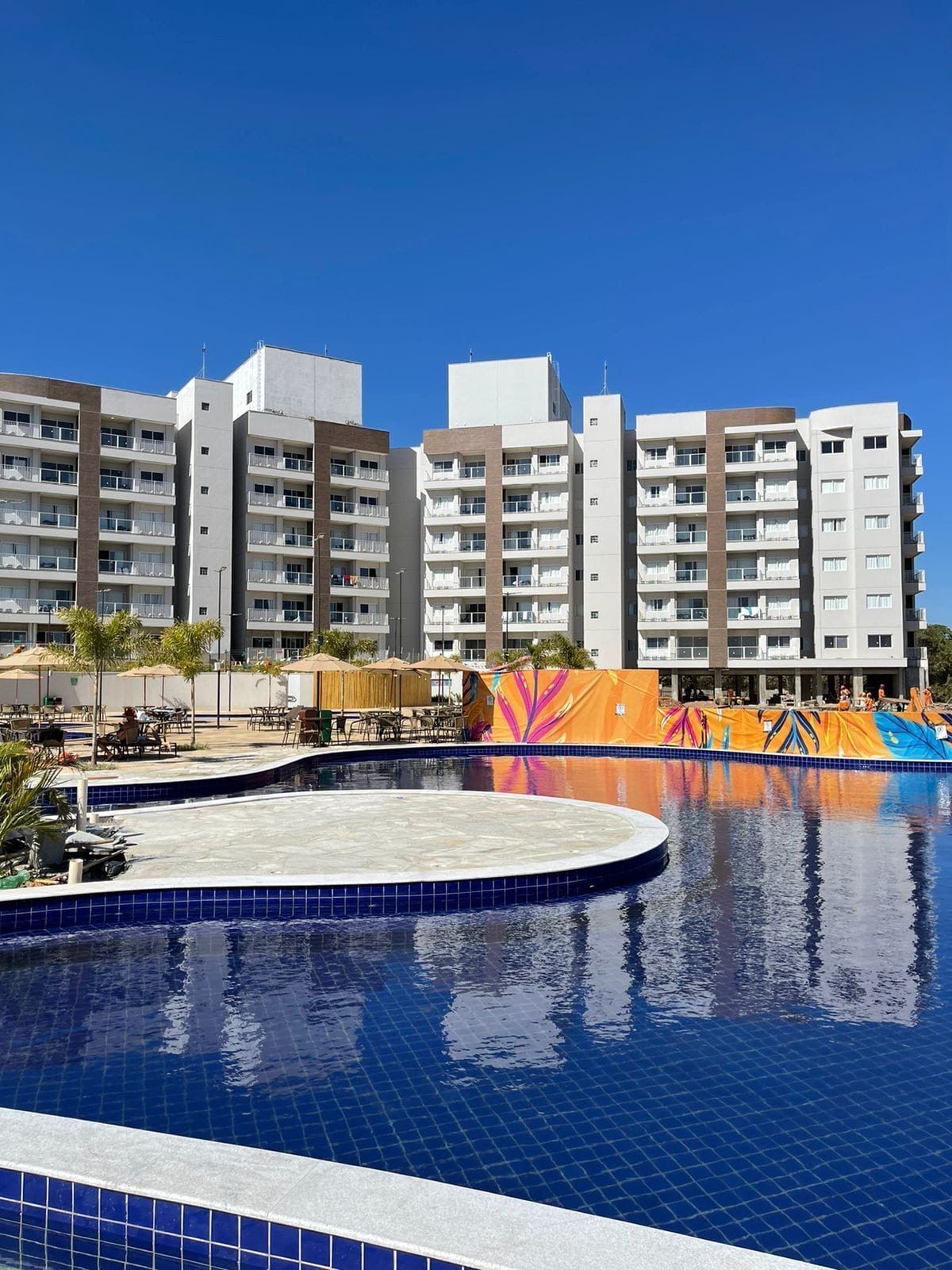 A hotel with multiple floors, a swimming pool, and outdoor seating areas.