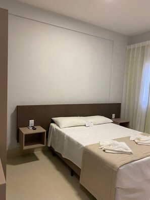 Ein Hotelzimmer mit einem Einzelbett, einem Nachttisch und einem Beistelltisch.