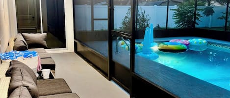 A modern living room with a large window overlooking a swimming pool area.