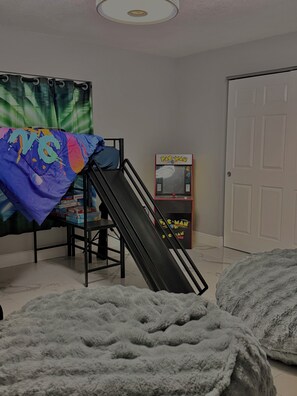 A room with a bunk bed, a Pac-Man arcade machine, and a door. - 4BR Home • Private Pool • Themed rooms • Sleeps 14 (Spring Hill)