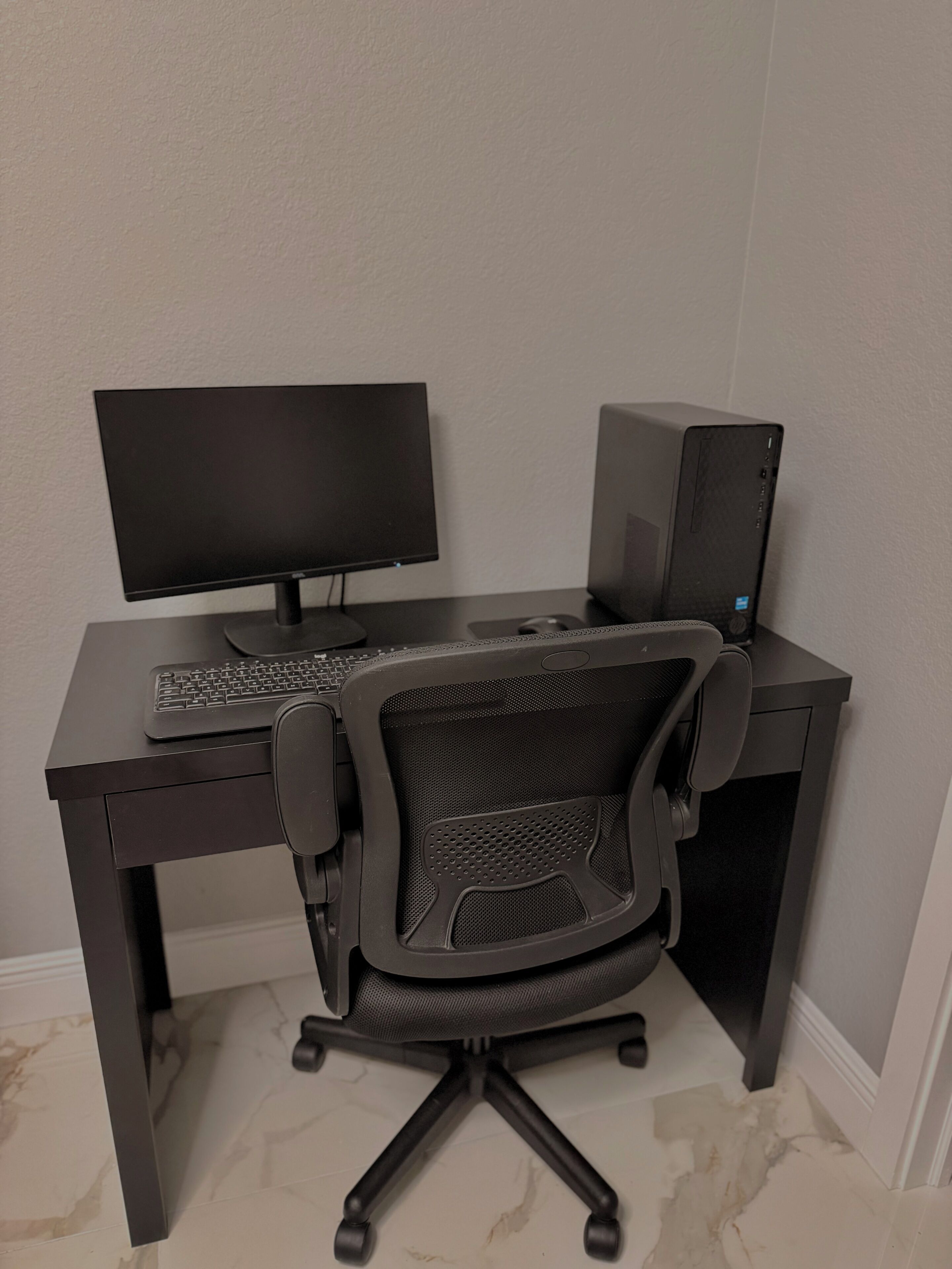 A computer desk with a monitor, keyboard, and tower PC.