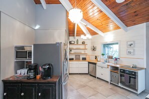 Una cucina moderna con mobili bianchi, un frigorifero in acciaio inossidabile, una macchina per caffè e una lavastoviglie.
