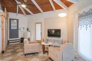A living room with a TV, two sofas, a coffee table, and a ceiling fan. - Private 3-acre retreat with hot tub and fire pit (Rutherford County)