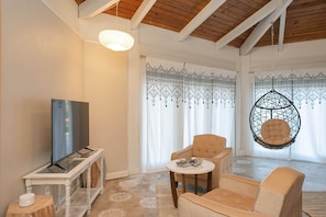 A living room with a television, two armchairs, a hanging chair, and patterned curtains. - Private 3-acre retreat with hot tub and fire pit (Rutherford County)
