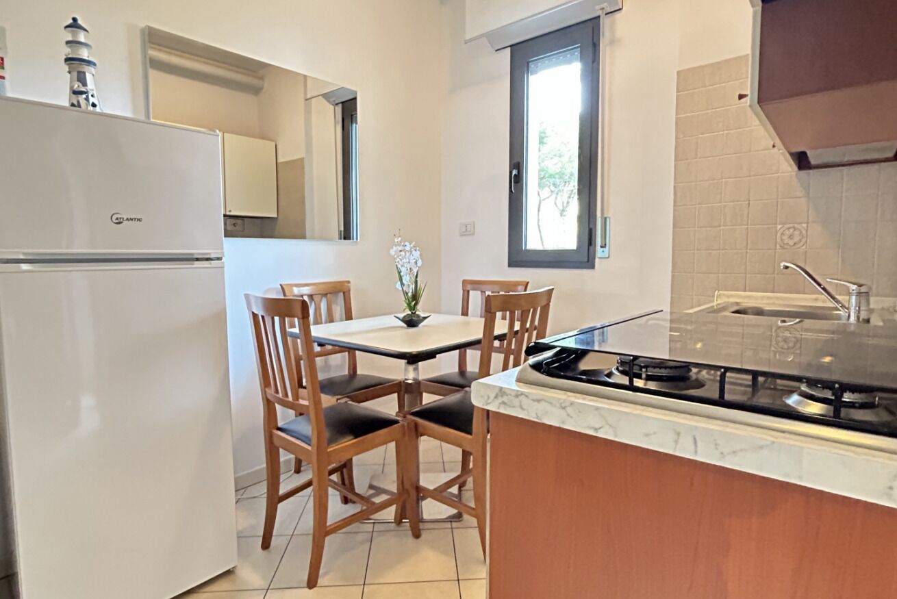 Una cucina compatta con frigorifero, un tavolo da pranzo con sedie, piano cottura a gas e una finestra vista.