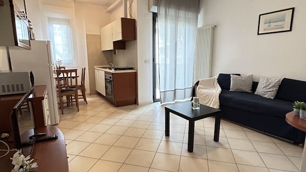 Ein modernes Wohnzimmer mit einem dunkelgrauen Sofa, einem Couchtisch und einem Essbereich mit Tisch und Stühlen.