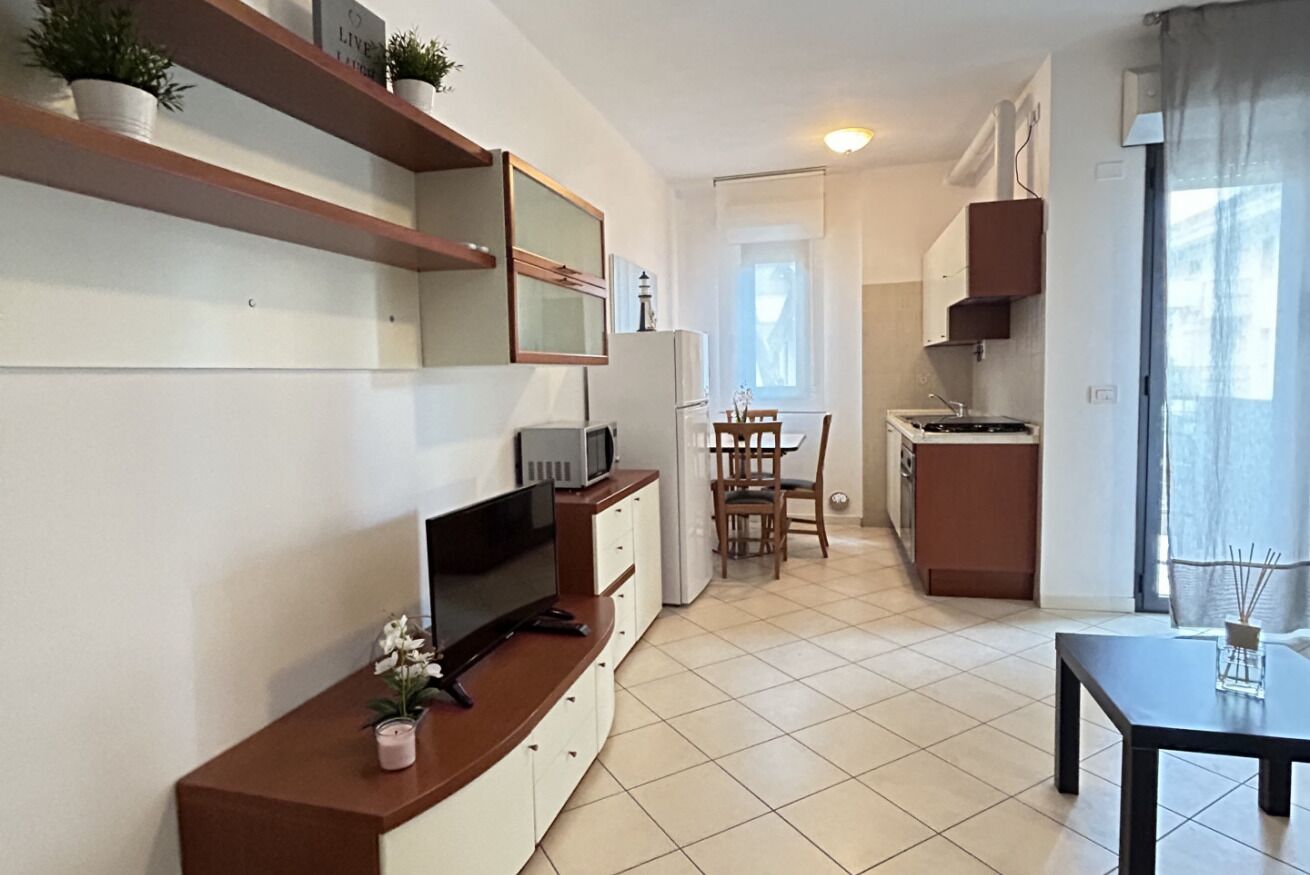 A modern kitchen with a dining area, a TV, and a small table with a candle.