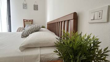 A neatly made bed with a wooden headboard, a potted plant, and two wall decorations with motivational phrases.