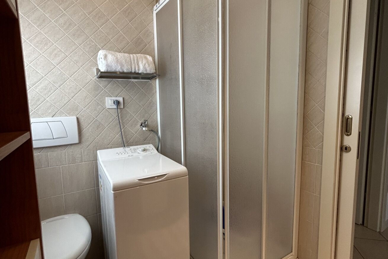 Ein Badezimmer mit Waschmaschine, Handtuchhalter und Toilette.