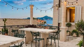 An outdoor patio with a stone floor, green metal chairs, and a table.