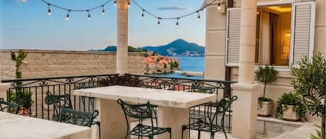 An outdoor patio with a stone floor, green metal chairs, and a table.