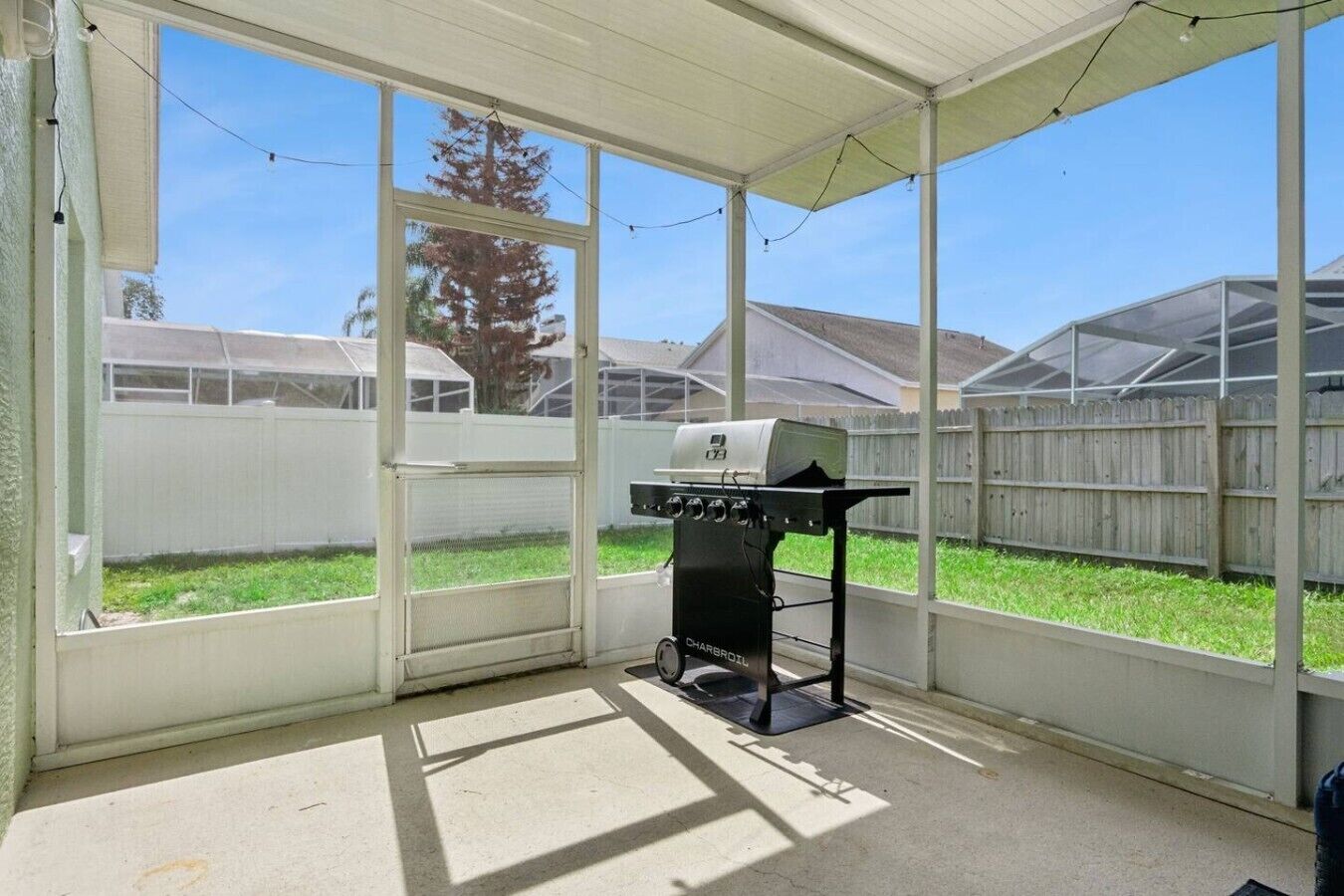 Un espace extérieur abrité, doté d’un barbecue, de grandes fenêtres et offrant une vue sur le jardin.