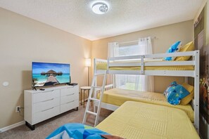Ein Schlafzimmer mit Etagenbetten, einem Fernseher, einem Schminktisch und einem Fenster mit Vorhängen.