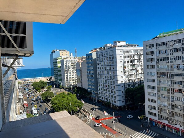 A high-rise building with multiple floors, a clear view of the sea, and a busy street with cars and pedestrians. - Vrbo Property (Rio de Janeiro)