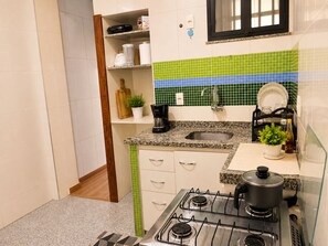 A compact kitchen with a gas stove, a sink, and a countertop. - Vrbo Property (Rio de Janeiro)