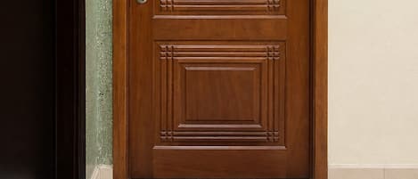 A wooden door with a number plate, a keyhole, and a doorbell.