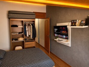 A bedroom with a bed, a wardrobe, a TV, and a shelf with books. - Vrbo Property (Rio de Janeiro)