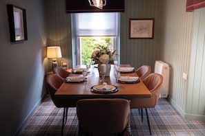 A dining room with a wooden table set for six, surrounded by leather chairs. - Fairytale Scots Baronial Coach House in Ballater, near Balmoral Castle (Ballater)