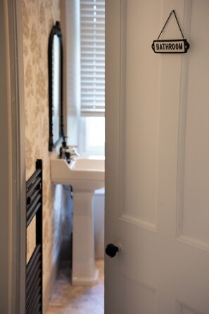 Ein Badezimmer mit einem weißen Waschbecken und einem Schild, das den Raum kennzeichnet.