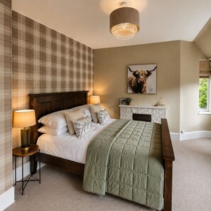 A bedroom with a bed, bedside lamps, a fireplace, and a painting on the wall. - Fairytale Scots Baronial Coach House in Ballater, near Balmoral Castle (Ballater)