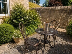 An outdoor patio with a metal table and chairs, a bottle of wine, and a potted plant. - Fairytale Scots Baronial Coach House in Ballater, near Balmoral Castle (Ballater)