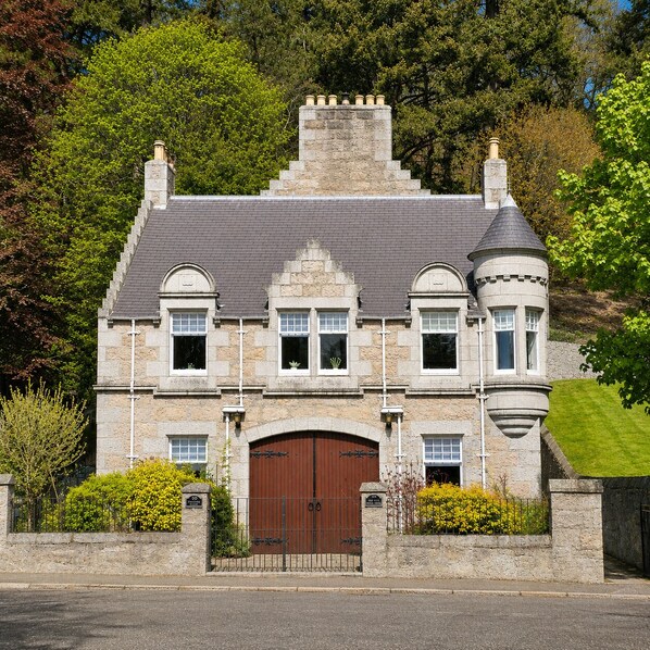A stone building with a large central entrance, multiple windows, and a turret. - Fairytale Scots Baronial Coach House in Ballater, near Balmoral Castle (Ballater)