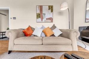 A beige sofa with multiple cushions, a floor lamp, and a painting on the wall. - 2 Bedroom House at Buxton Peak District (Buxton)