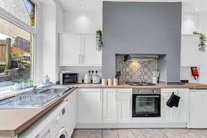 A modern kitchen with white cabinets, a microwave, a kettle, and a stove. - 2 Bedroom House at Buxton Peak District (Buxton)