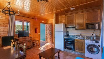 Un interior de madera con zona de comedor, cocina y televisor.