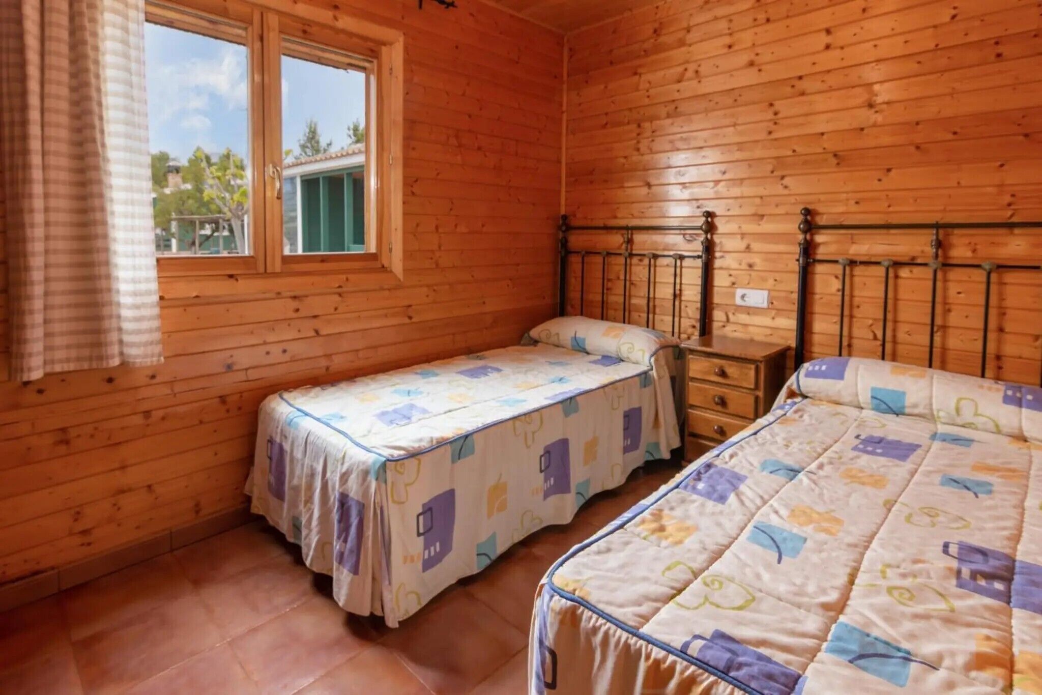 Ein Zimmer mit Holzboden, zwei Betten und einem Fenster.