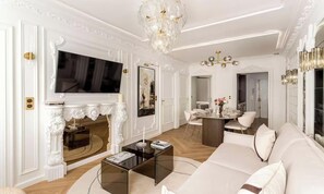 Un salon luxueux doté d’une cheminée, d’un grand téléviseur à écran plat, d’un lustre et d’un coin repas.