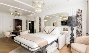 Une chambre à coucher moderne avec un lit, des tables de chevet, un bureau et un grand miroir.