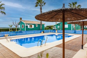 A swimming pool with a blue water feature, surrounded by a blue fence, and adjacent to a building with a green exterior. - Apartment 'Los Albares' with Mountain View, Wi-Fi and Air Conditioning (Las Canales)