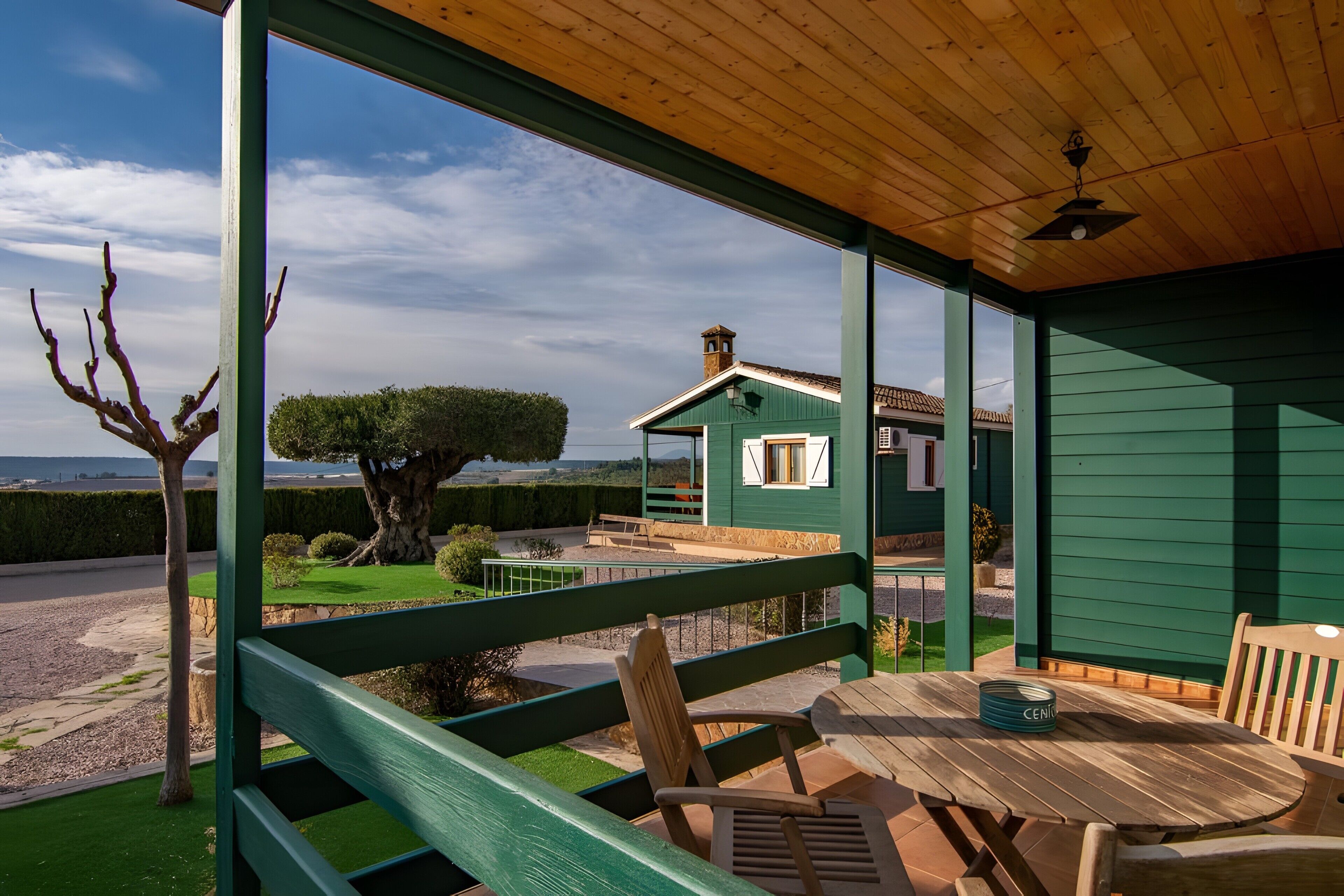 A covered outdoor seating area with a view of a house and landscape.