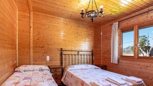 Ein Zimmer mit zwei Betten, Holzwänden, einem Fenster und einer Chandelier.