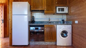 A compact kitchen with wooden cabinets, a white refrigerator, a microwave, a built-in oven, and a front-loading washing machine.