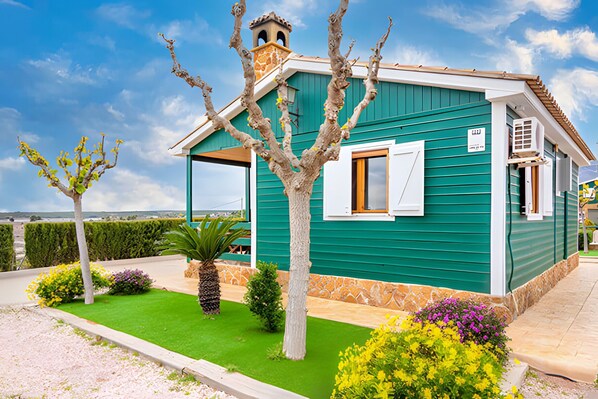 A small, single-story building with a green exterior and a white window.