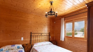 Een houten kamer met twee bedden, een kroonluchter en een raam met uitzicht.