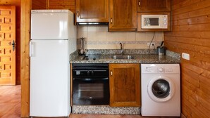 Cocina compacta equipada con refrigerador, microondas, lavaplatos, lavadero y lavadora.