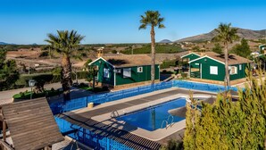 Una zona residencial con piscina, casas verdes y palmeras.