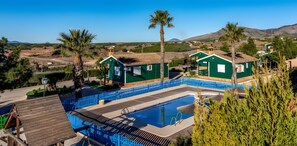 A residential area with a swimming pool, green houses, and palm trees.