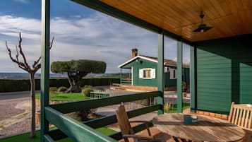 Een overdekt terras met uitzicht op een huis en het omliggende landschap.