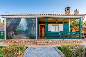 A building with a stone facade, a covered porch, and a mural on the side. - Apartment 'Las Canales' with Mountain View, Wi-Fi and Air Conditioning (Las Canales)