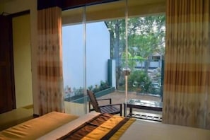 A bedroom with a bed, a window, and a view of a garden.