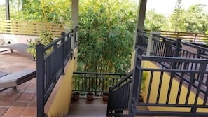 A covered outdoor area with a staircase leading to a higher level, surrounded by greenery.