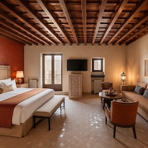 A hotel room with a bed, a sofa, a TV, and a fireplace. - YANGUAS NAZARI PALACE (Albaicin)