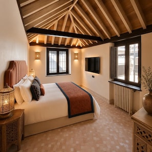 A bedroom with a large bed, a TV mounted on the wall, and a window with a view. - YANGUAS NAZARI PALACE (Albaicin)