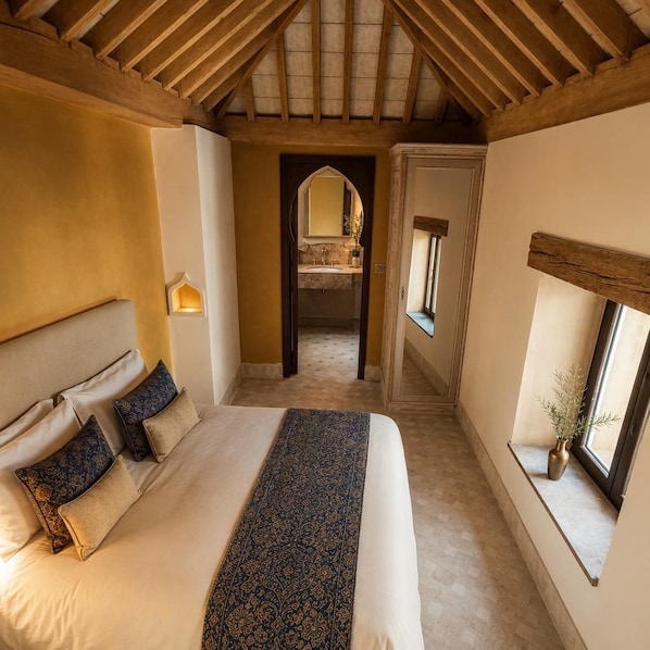 Une chambre avec un grand lit, une table de chevet, une fenêtre donnant sur un beau paysage et un plafond en bois.