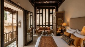 A hotel room with a large bed, a sofa, a small table, and a balcony. - YANGUAS NAZARI PALACE (Granada)