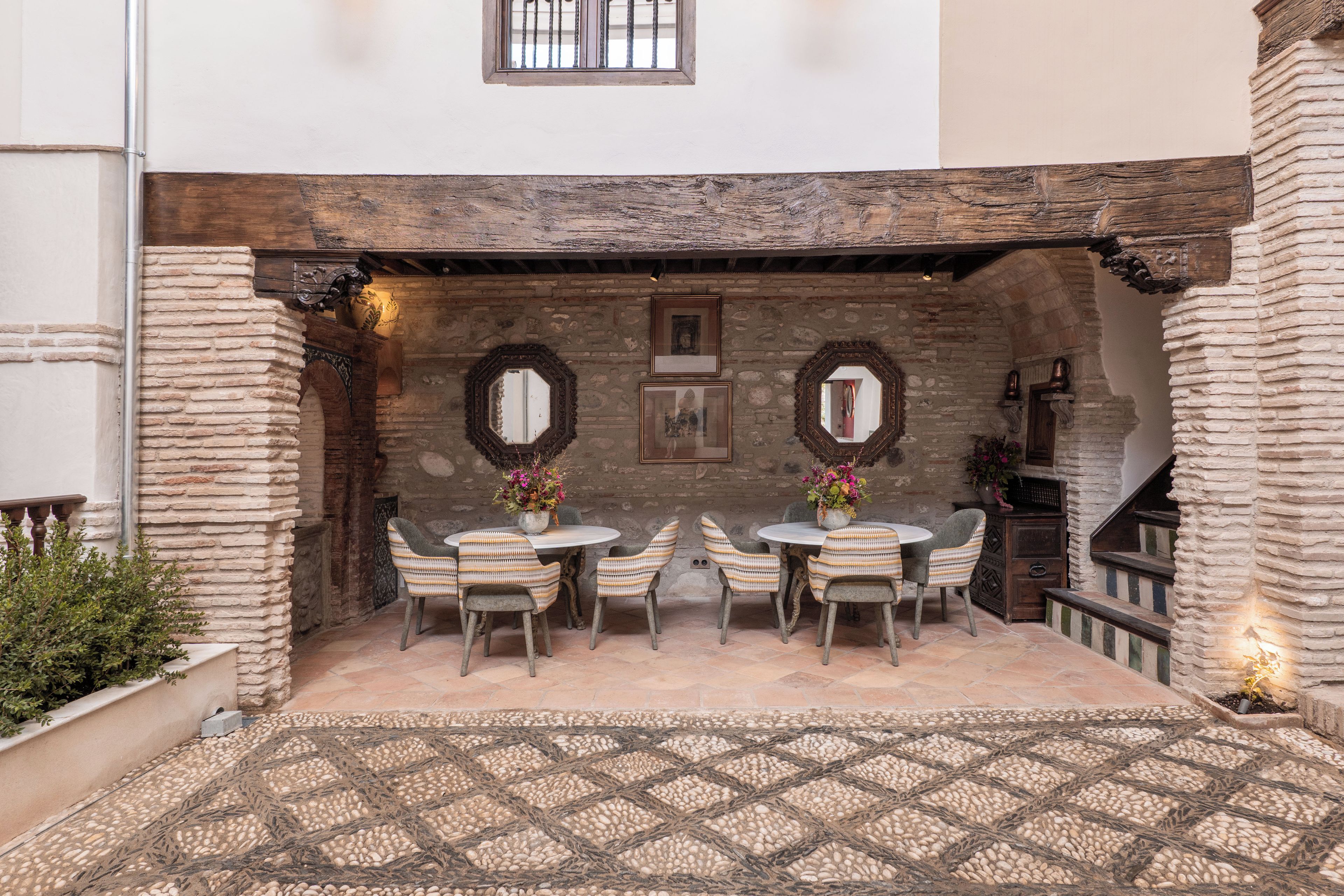 An outdoor patio with stone walls, a tiled floor, and a table with chairs.
